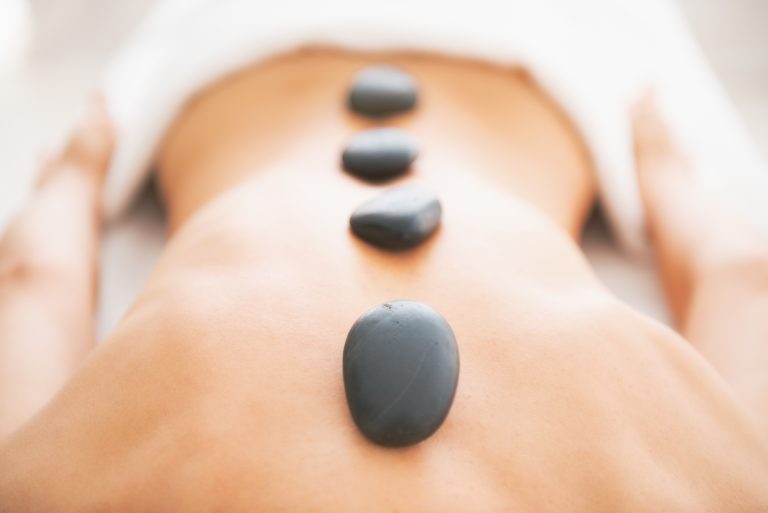 Closeup on young woman receiving hot stone massage